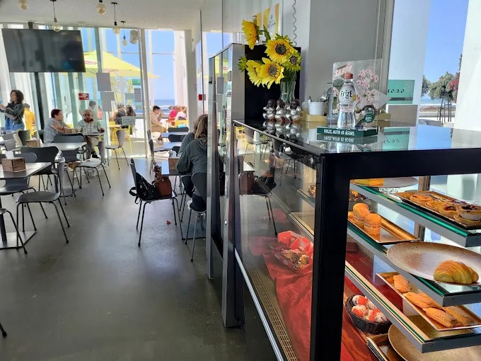 Interior com vitrine de pastelaria e vista para o mar